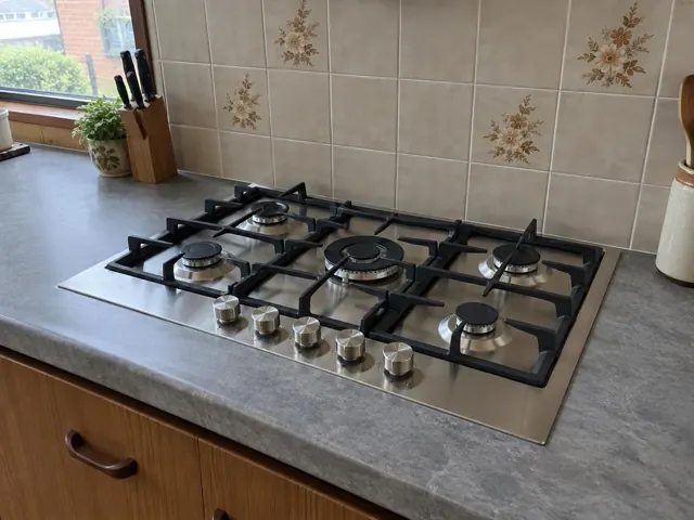 Stainless steel gas cooktop in a tiled kitchen with grey benchtop and window in Gateshead